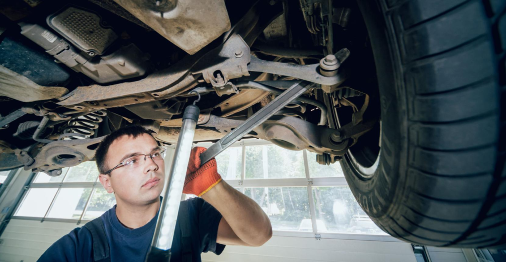 Mechanic inspecting car suspension system